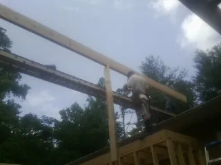 Carpenter setting a ridge beam over a new addition frame — Ice Dam Removal by Roofing Brothers in West Camp