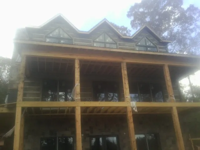 Dormers and porch framing on a large log home under construction — Roof Coating work by our crew in West Camp