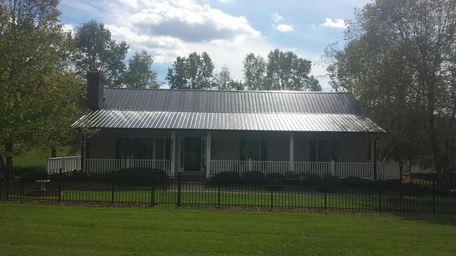 Gray metal roof on a brick ranch with a full width front porch — Gutter Guard Installation work by our crew in West Camp