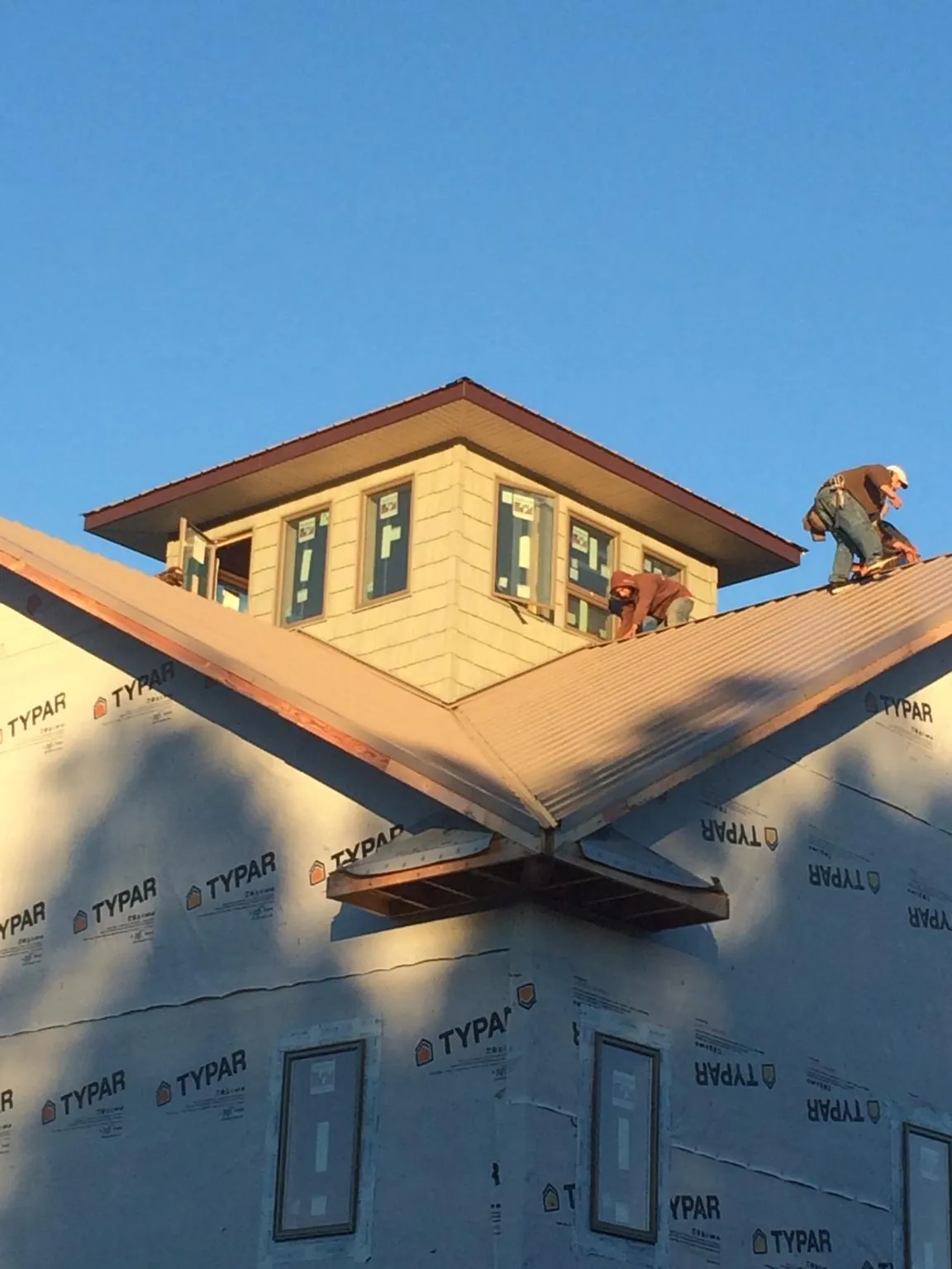 Roofers working around a rooftop cupola on a new metal roof at sunset — Roof Waterproofing in West Camp by Roofing Brothers